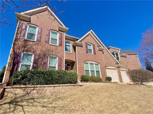 multi unit property featuring a garage, brick siding, and driveway