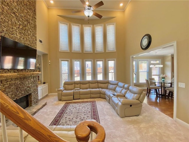 living area featuring baseboards, a fireplace, a ceiling fan, and crown molding