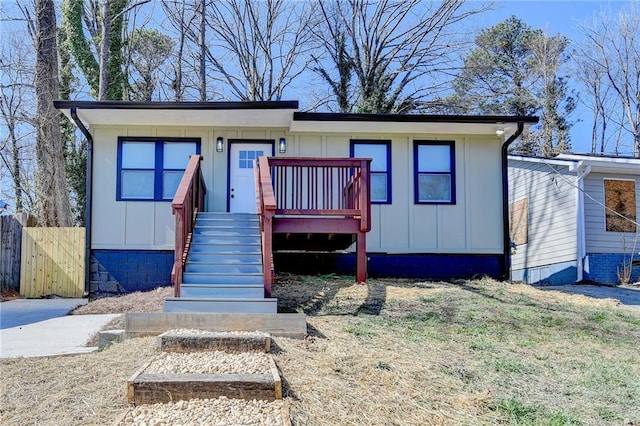 view of front of home with a front lawn, board and batten siding, and fence