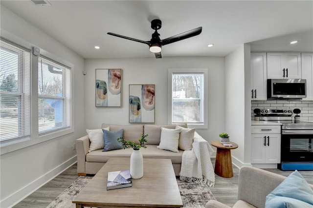 living area featuring light wood-style floors, baseboards, and recessed lighting