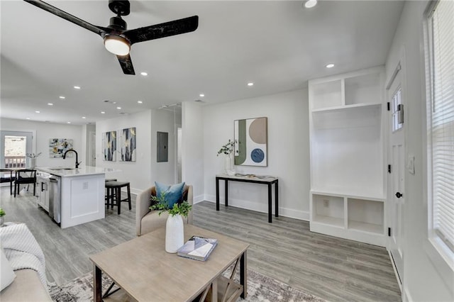 living room with light wood-type flooring, electric panel, and recessed lighting