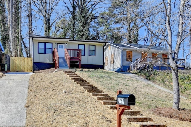 view of front facade featuring stairs, board and batten siding, and fence