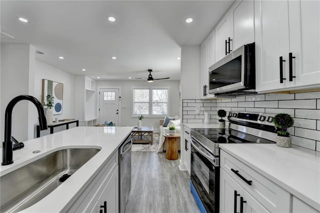 kitchen with light countertops, appliances with stainless steel finishes, a sink, and white cabinets