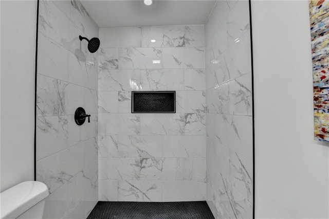 bathroom featuring a tile shower and toilet