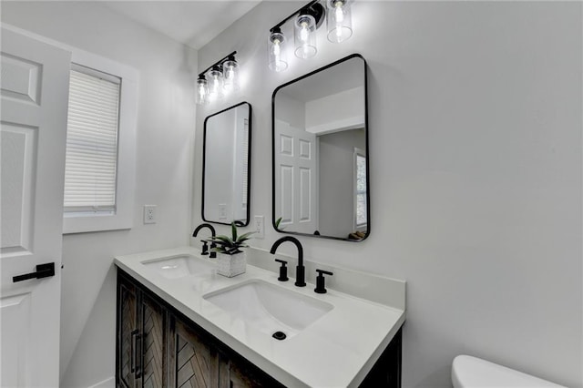 bathroom featuring double vanity, a sink, and toilet