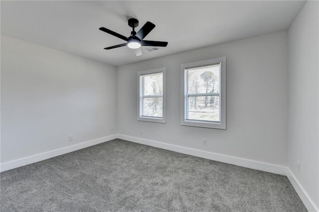 empty room featuring a ceiling fan, light colored carpet, visible vents, and baseboards