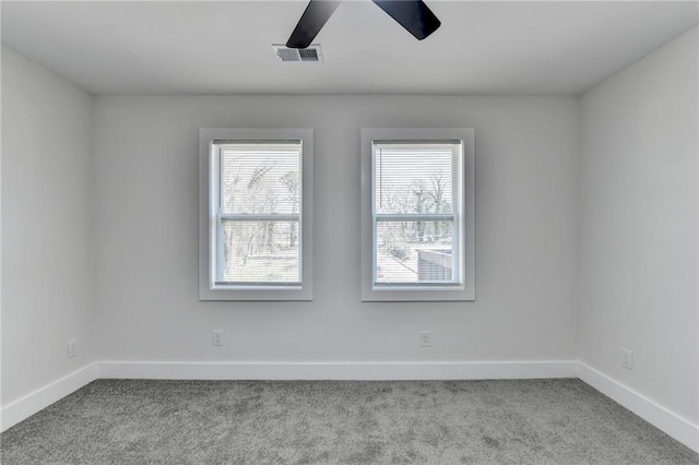 empty room featuring baseboards, visible vents, and light colored carpet