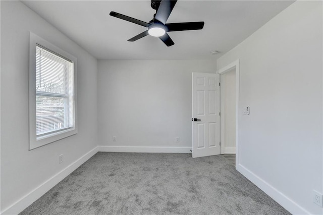 spare room with light colored carpet, ceiling fan, and baseboards