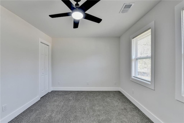 spare room featuring baseboards, a ceiling fan, visible vents, and light colored carpet