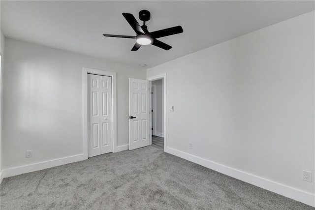 unfurnished bedroom featuring light carpet, ceiling fan, a closet, and baseboards