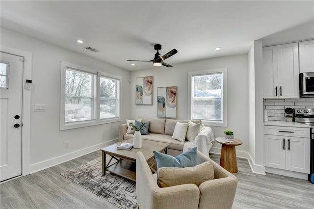 living room featuring light wood-type flooring, plenty of natural light, and baseboards