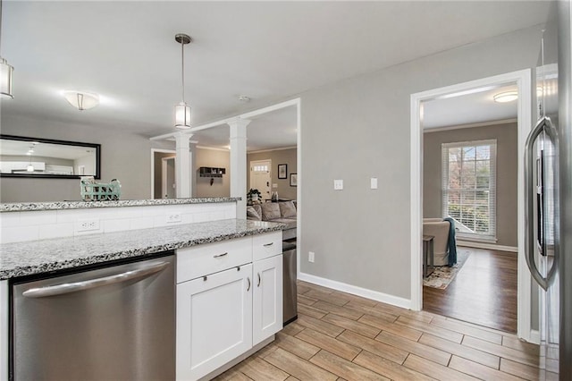 kitchen featuring ornate columns, light stone countertops, stainless steel appliances, pendant lighting, and white cabinets