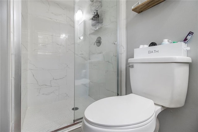 bathroom featuring a shower with door and toilet