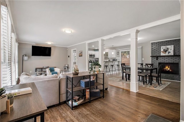 living room with hardwood / wood-style flooring, ornamental molding, and a brick fireplace