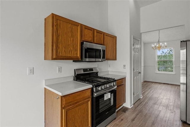 1910 Towne Park Dr, Mcdonough, GA 30252 - kitchen with stainless steel appliances, a chandelier, brown cabinets, light countertops, and wood finished floors