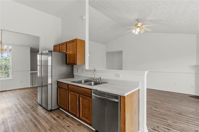 1910 Towne Park Dr, Mcdonough, GA 30252 - kitchen featuring appliances with stainless steel finishes, a sink, open floor plan, brown cabinetry, and light wood-style flooring