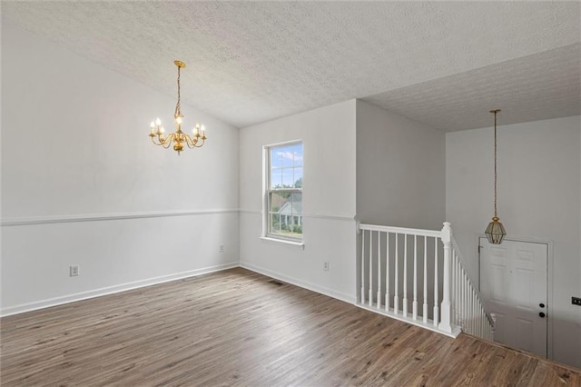 1910 Towne Park Dr, Mcdonough, GA 30252 - unfurnished room with a chandelier, wood finished floors, a textured ceiling, and baseboards