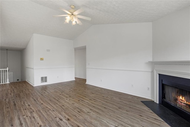 1910 Towne Park Dr, Mcdonough, GA 30252 - unfurnished living room with ceiling fan, wood finished floors, a textured ceiling, a fireplace with flush hearth, and vaulted ceiling