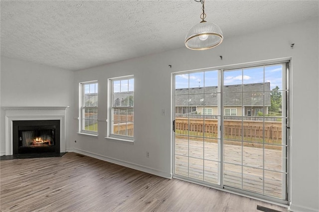 1910 Towne Park Dr, Mcdonough, GA 30252 - unfurnished living room featuring wood finished floors, a textured ceiling, a fireplace with flush hearth, and baseboards