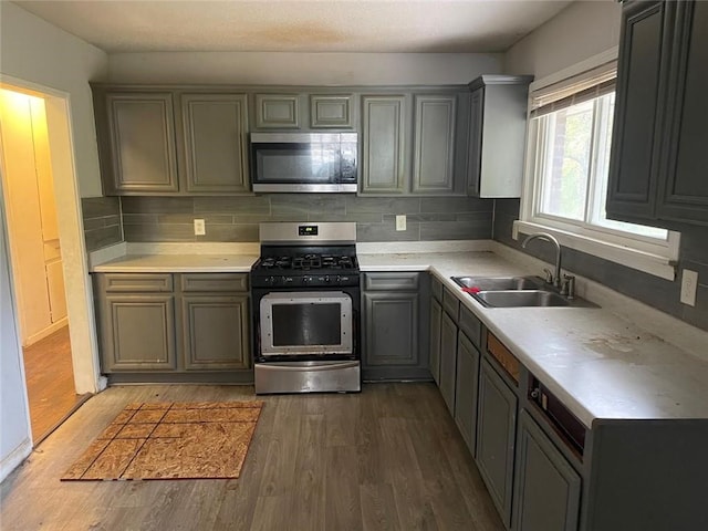 kitchen featuring dark hardwood / wood-style floors, tasteful backsplash, stainless steel appliances, and sink