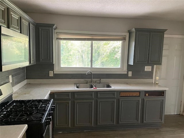 kitchen with black gas stove, backsplash, sink, a textured ceiling, and dark hardwood / wood-style flooring