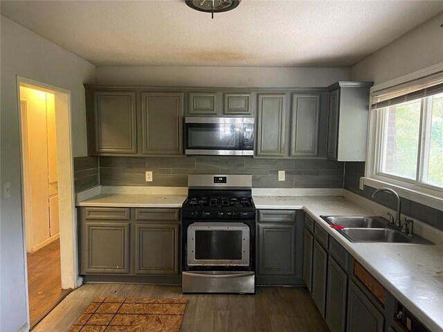 kitchen with hardwood / wood-style flooring, stainless steel appliances, sink, and backsplash