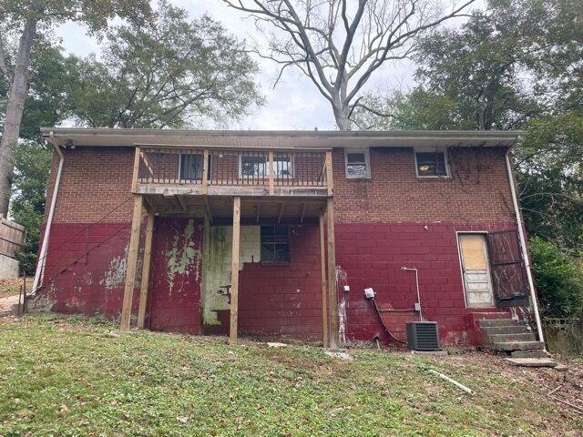 rear view of house with central AC and a lawn