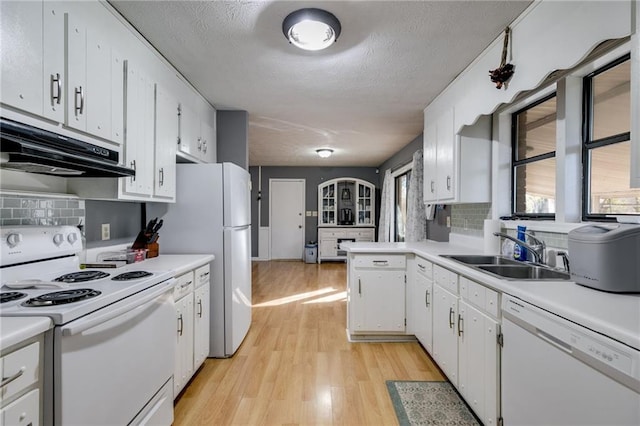 kitchen with extractor fan, backsplash, white appliances, white cabinets, and sink