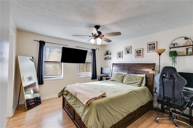 bedroom with a textured ceiling, ceiling fan, and light hardwood / wood-style flooring