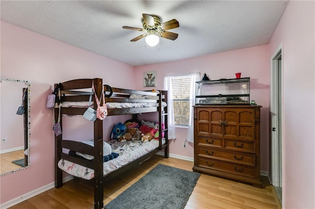 bedroom with ceiling fan, wood-type flooring, and a textured ceiling