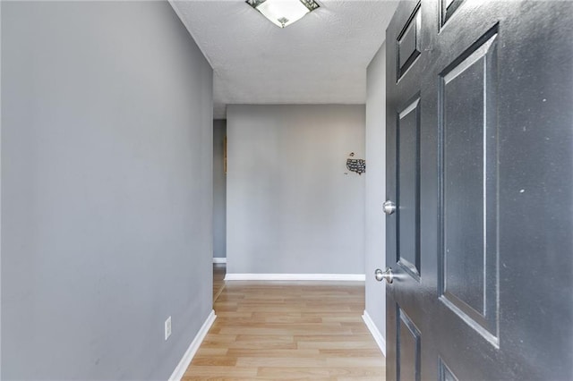 corridor with a textured ceiling and light wood-type flooring