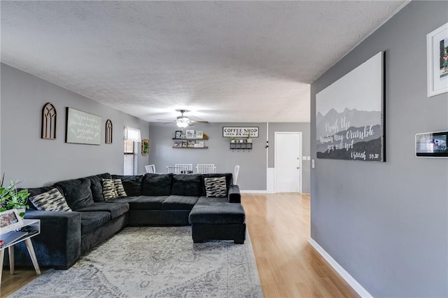 living room featuring ceiling fan, a textured ceiling, and hardwood / wood-style flooring