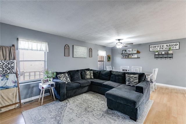 living room featuring ceiling fan, a textured ceiling, and hardwood / wood-style flooring