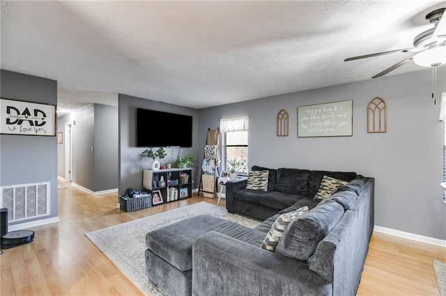 living room with ceiling fan, wood-type flooring, and a textured ceiling