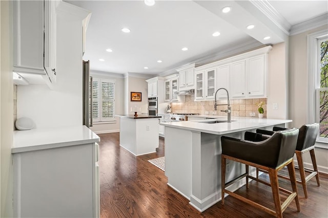 kitchen featuring white cabinetry, dark hardwood / wood-style flooring, sink, a kitchen breakfast bar, and kitchen peninsula