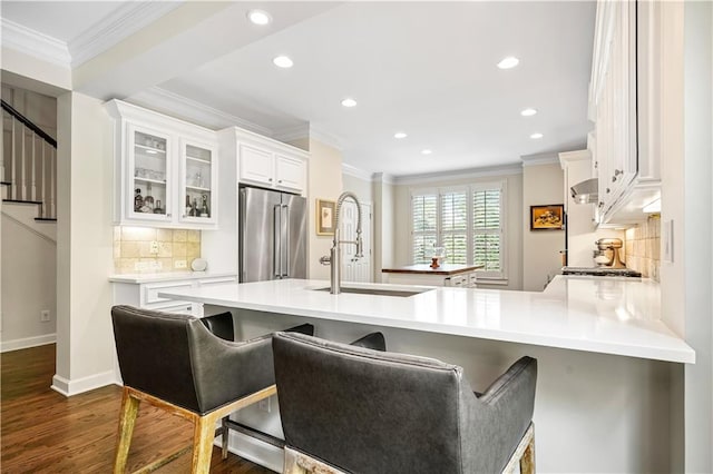 kitchen with white cabinets, kitchen peninsula, tasteful backsplash, dark hardwood / wood-style floors, and high quality fridge