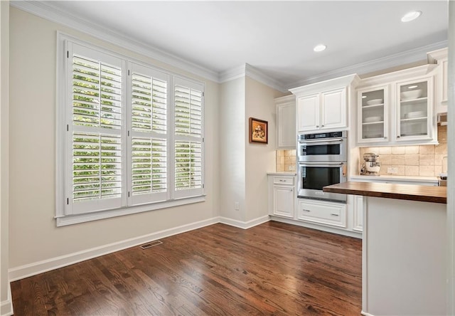 kitchen featuring butcher block counters, stainless steel double oven, a healthy amount of sunlight, and white cabinets