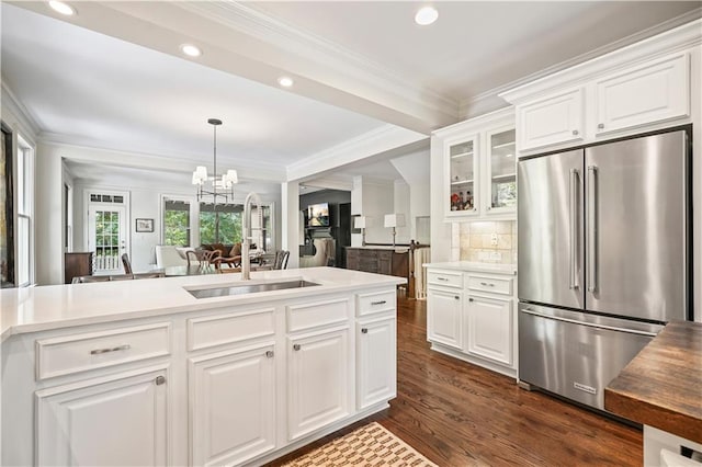 kitchen with white cabinets, high quality fridge, sink, and ornamental molding