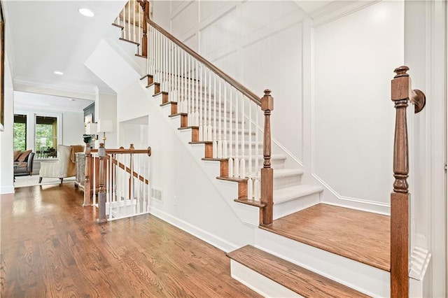 stairway featuring wood-type flooring and crown molding