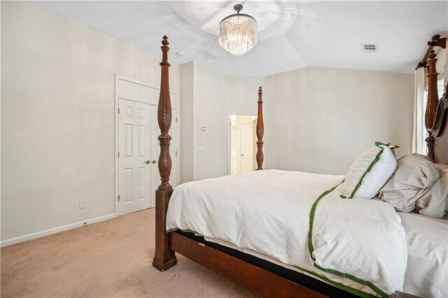 carpeted bedroom with vaulted ceiling and an inviting chandelier