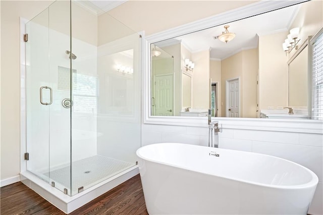 bathroom with ornamental molding, shower with separate bathtub, wood-type flooring, and tile walls