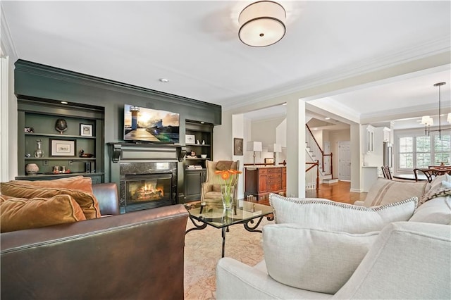 living room with ornamental molding, a fireplace, light hardwood / wood-style floors, and built in features