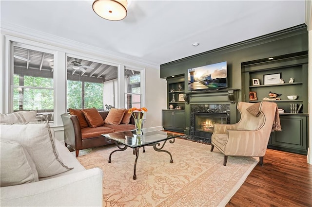 living room featuring ornamental molding, hardwood / wood-style floors, a high end fireplace, and a healthy amount of sunlight