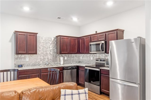 244 Grand Central Way, Cartersville, GA 30120 - kitchen with appliances with stainless steel finishes, decorative backsplash, light wood-style flooring, and reddish brown cabinets