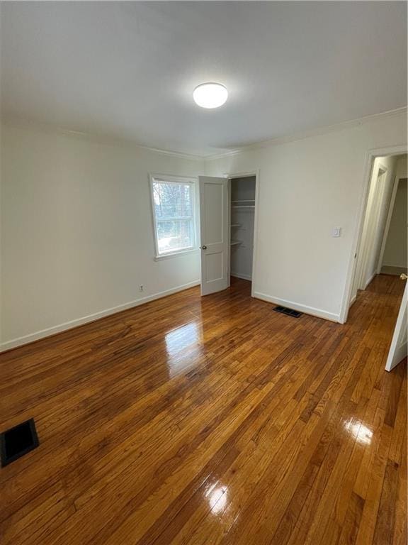 unfurnished bedroom featuring wood-type flooring, visible vents, and baseboards