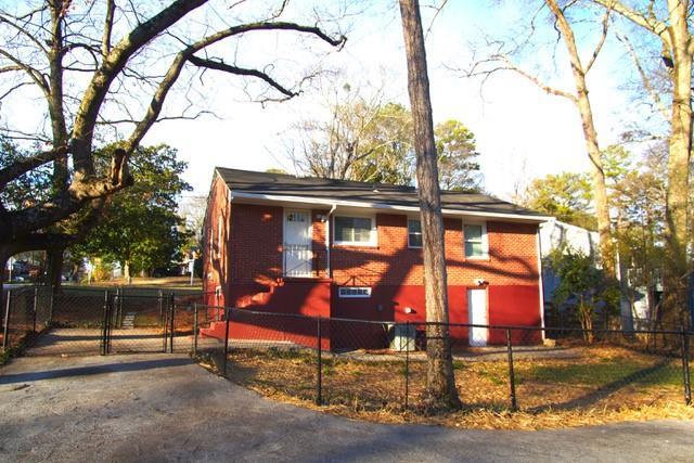 view of side of property with a fenced front yard, a gate, and brick siding