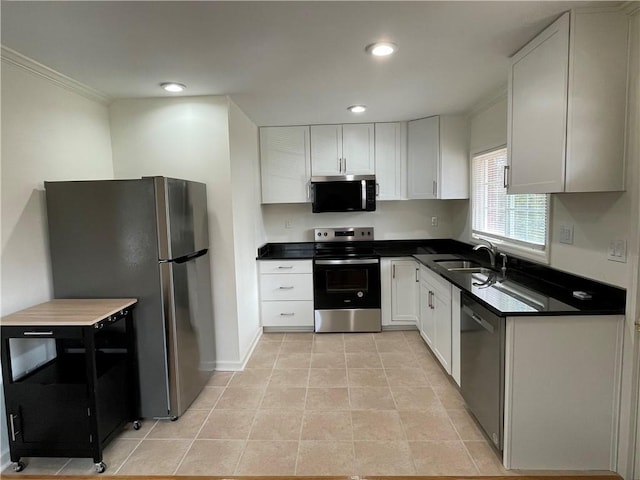 kitchen featuring stainless steel appliances, dark countertops, white cabinetry, and a sink