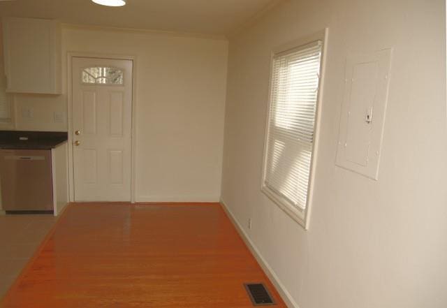 hall featuring light wood-style flooring, electric panel, visible vents, and baseboards