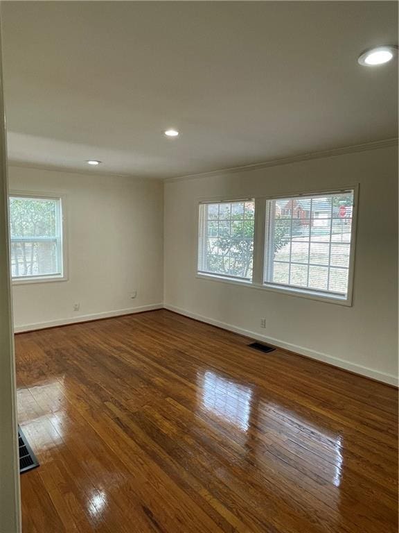 unfurnished room with dark wood-style floors, baseboards, visible vents, and a wealth of natural light