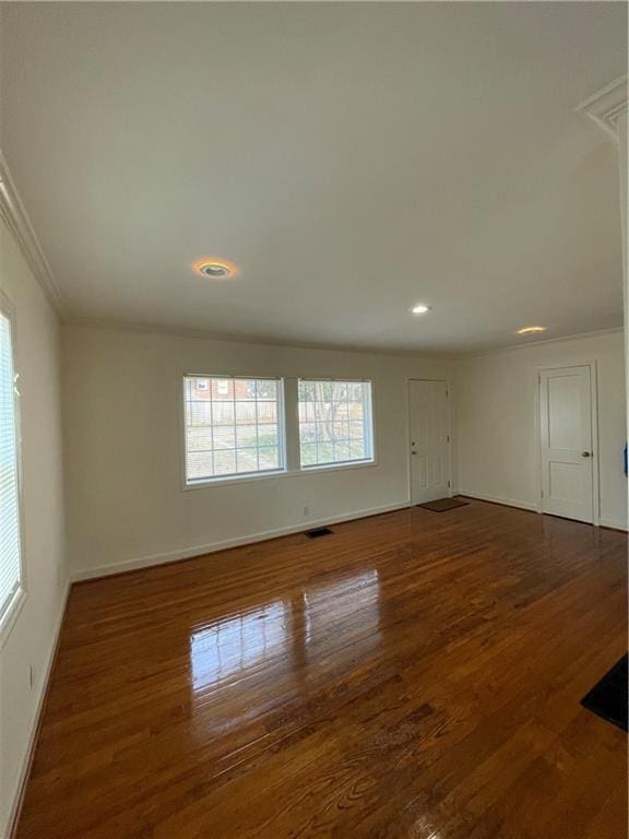 empty room with visible vents, baseboards, dark wood finished floors, and crown molding